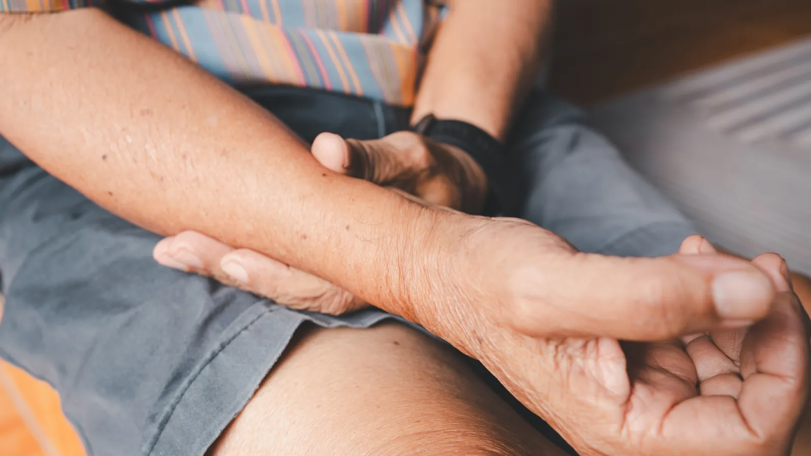 A hand supporting the underside of an adult’s forearm.