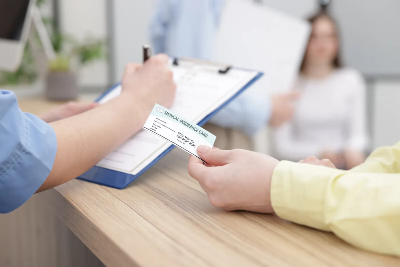 A patient handing a medical insurance card to staff at the front desk of Florida Vascular Care.